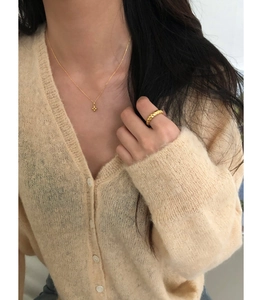 Collier croix en argent 925 doré et bague texturée portés par un mannequin au style chic