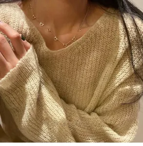 Delicate gold 925 silver necklace with multiple heart charms worn on a cozy sweater