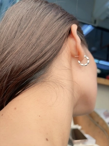 Close-up of S925 sterling silver beaded hoop earrings worn on a model's earlobe