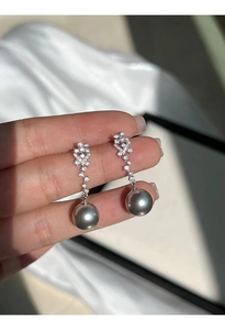 Macro shot of silver pearl drop earrings with sparkling pavé crystal flower clusters