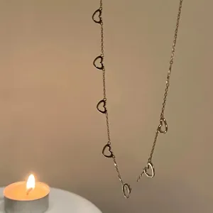 Close-up of a gold 925 silver necklace with multiple heart-shaped pendants on warm background