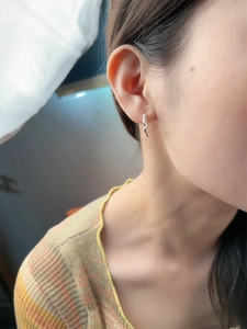 Close-up of small S925 sterling silver beaded hoop earrings worn on a female ear
