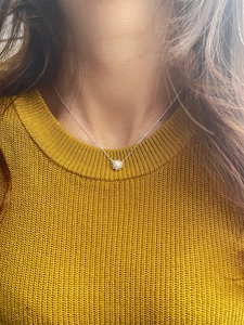 Detailed close-up of a sterling silver daisy pendant necklace worn on a model's neck