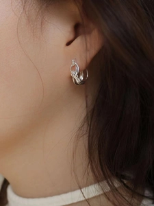Silver multi-layer twisted hoop earrings in minimalist hollow design worn by model