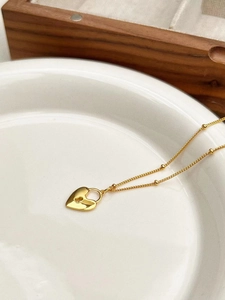 Élégant collier avec pendentif cœur en argent 925 doré disposé dans un plat en céramique