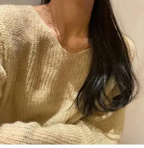 Close-up of 925 sterling silver heart necklace worn with a cream V-neck sweater