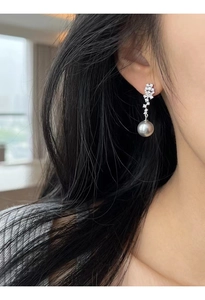 Macro detail of S925 silver leaf earrings with zircon pavé and a round grey pearl