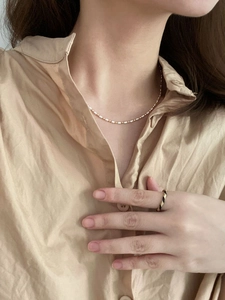 Detail of S925 silver beaded necklace and twisted ring on a khaki shirt collar