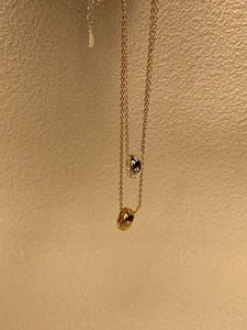 Vue détaillée de colliers pendentifs étoile argentés et dorés sur un mur beige