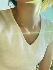 Close-up of a silver heart necklace with blue opal inlay on a delicate beaded chain