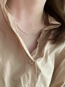Close-up of minimalist S925 silver necklace with white beads and gold metal accents