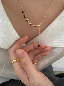 Gros plan d'un collier doré avec pierre noire et bague matelassée sur le mannequin