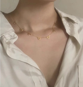 Close-up of a minimalist gold sterling silver necklace with delicate hollow heart charms