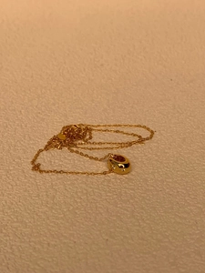 Détail du collier pendentif ovale doré avec trois accents étincelants en zircon