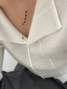 Gros plan d'un collier en Y doré avec cinq pierres précieuses noires rectangulaires