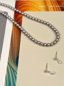 Detail of s925 silver leaf earrings and grey pearl necklace on artistic magazine background