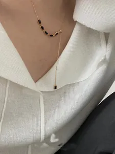 Gros plan du collier en Y en argent 925 doré avec pierres précieuses noires sur modèle
