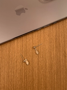 Minimalist S925 silver leaf earrings in gold finish on a warm wooden background