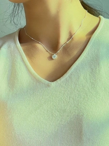 Close-up of 925 silver heart necklace with radial texture and blue zircon on a model