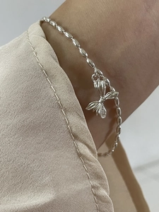 Close-up of a minimalist 925 sterling silver beaded bracelet with a bow charm pendant