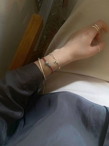 Minimalist silver open bangle and gold rings set worn with red woven bracelet