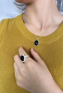 Detailed view of 925 sterling silver black onyx necklace and ring set on model