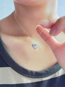 Sterling silver heart pendant necklace with sunray texture worn on neck