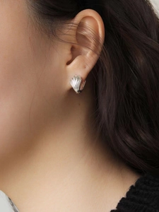 Gros plan de boucles d'oreilles coquillage en argent 925 portées par un mannequin