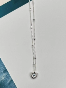 Detailed view of silver heart pendant with radial texture and light blue gemstone inlay