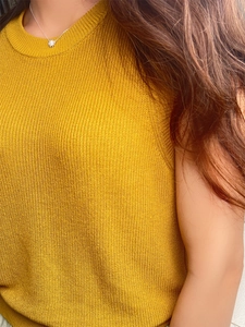 Close-up of mustard yellow sleeveless knit top with refined ribbed texture and crew neck