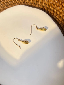Detailed macro shot of golden conch shell earrings with spiral texture on white tray