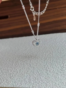 Close-up of heart-shaped 925 silver necklace with radial patterns and blue gemstone