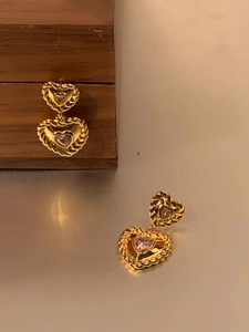 Détail de boucles d'oreilles cœur rose en zircon avec bordure dorée et argent 925