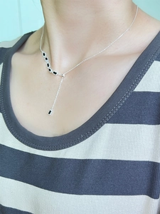 Détail d'un collier en Y en argent 925 avec pendentifs en pierre noire porté au cou