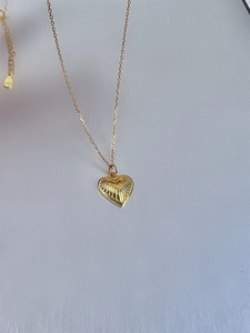 Detail of 18k gold heart pendant with radial texture and S925 sterling silver hallmark