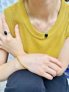 Close-up of 925 silver black agate necklace and ring on model wearing yellow sweater