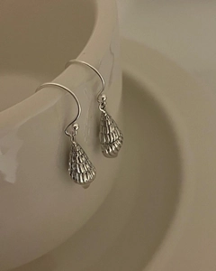 Detail view of 925 sterling silver conch shell earrings on a white ceramic dish