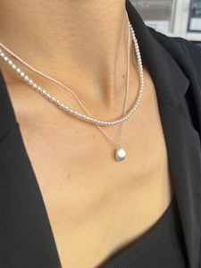 S925 sterling silver pearl necklace with brushed oval pendant on a black blazer background