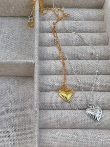 Detail of 925 sterling silver heart necklaces with textured radial patterns in gold and silver