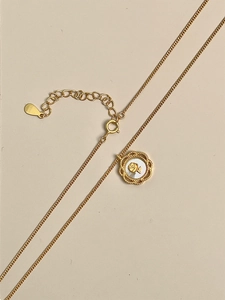 Détail du collier à pendentif fleur dorée avec relief de rose et fermoir ajustable