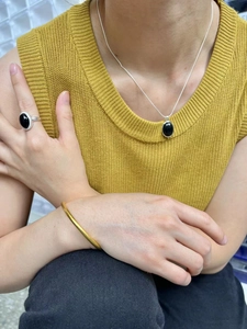 Close-up of 925 silver black onyx necklace and ring set worn with a gold bangle