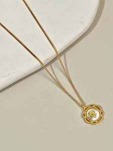 Gros plan du collier en argent 925 doré avec pendentif nacre et relief de rose dorée