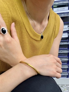 Detail view of model wearing a black agate necklace, ring, and gold bracelet set
