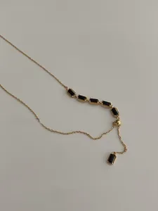 Vue détaillée du collier plaqué or avec cinq pierres noires serties et un fermoir ajustable