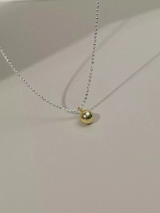 Close-up of minimalist 925 silver beaded chain with a polished gold ball pendant
