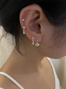 Detail of four-piece S925 silver earring set with shell and zircon studs on ear