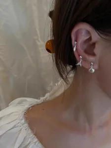 Detail of s925 silver shell and mermaid tail stud earrings set worn by a model