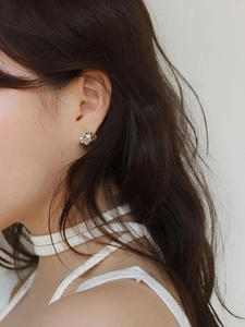 Close-up of minimalist silver stud earrings with opal stone on a model's ear