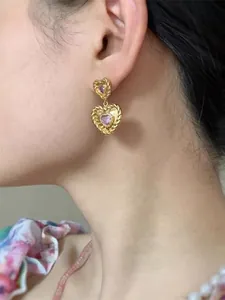 Détail de boucles d'oreilles torsadées en or vintage avec cœurs en zircon rose