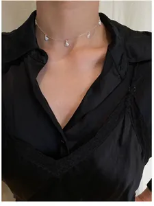 Detailed close-up of a silver shell choker necklace worn over a black silk shirt